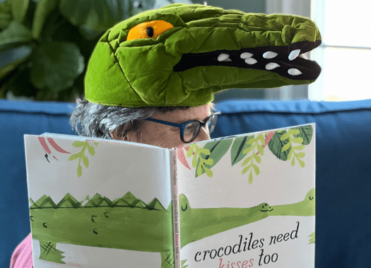 Mrs Katz wearing a crocodile hat while reading the picture book crocodiles need kisses too